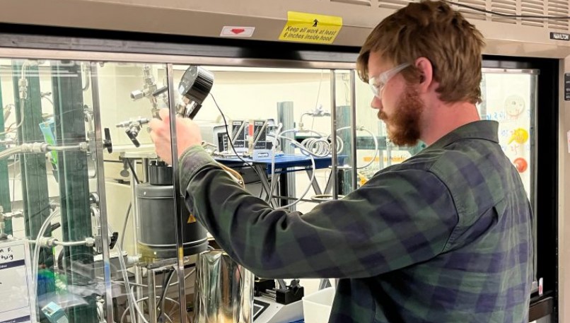 Graduate student RJ Conk adjusts a reaction chamber in which mixed plastics are degraded into the reusable building blocks of new polymers